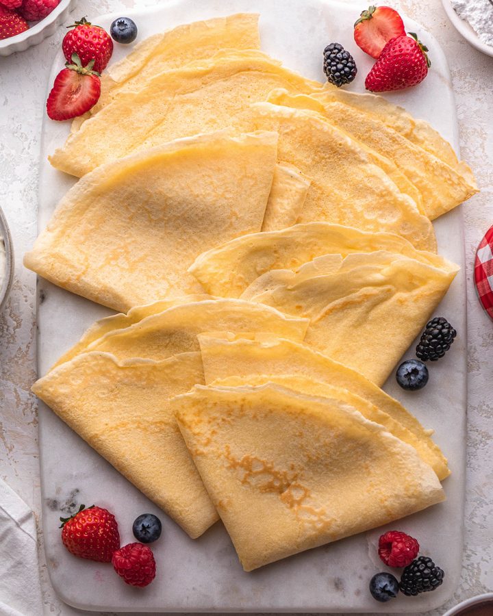 10 crepes on a serving board with berries