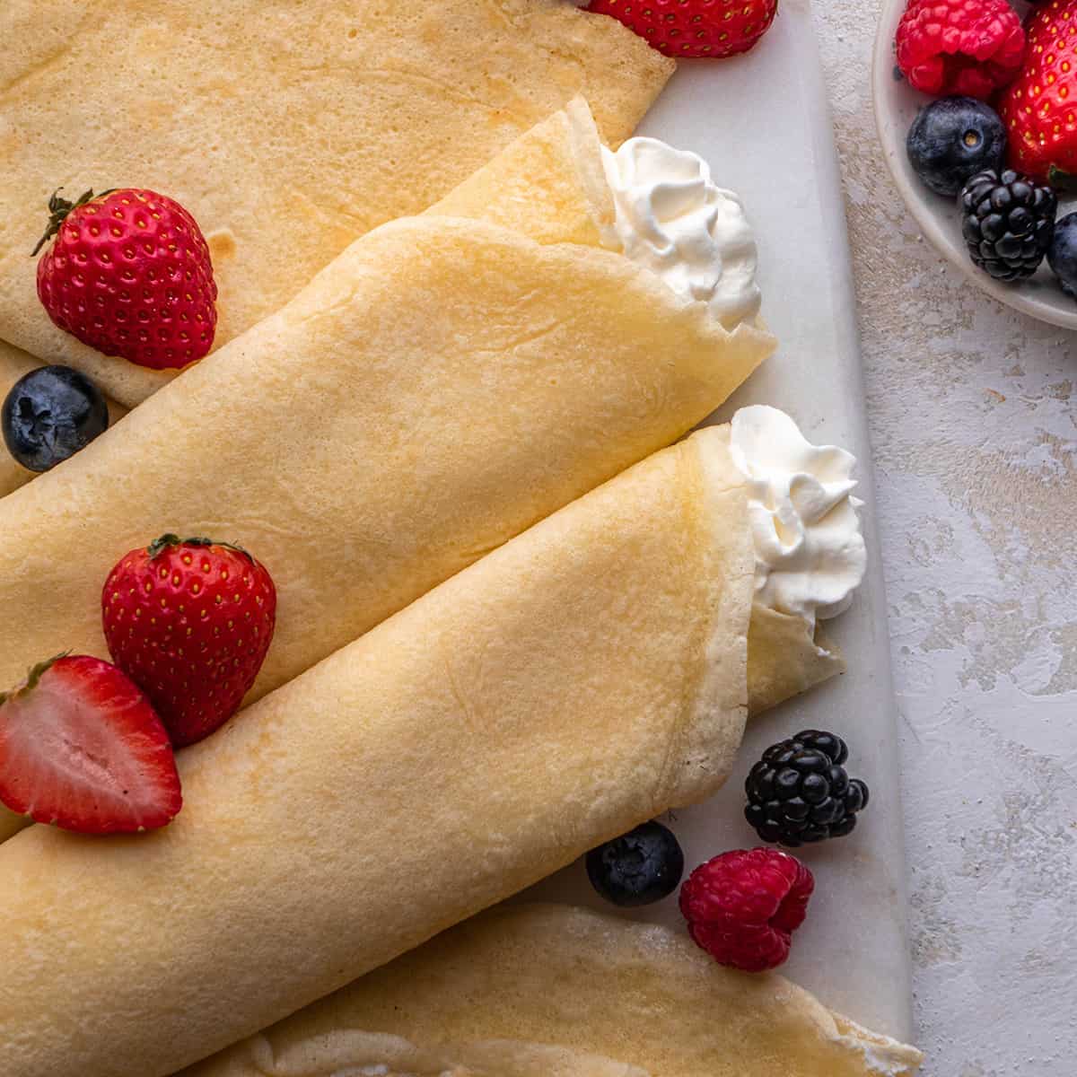 two crepes filled with whipped cream topped with berries