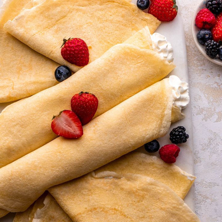 two crepes filled with whipped cream topped with berries