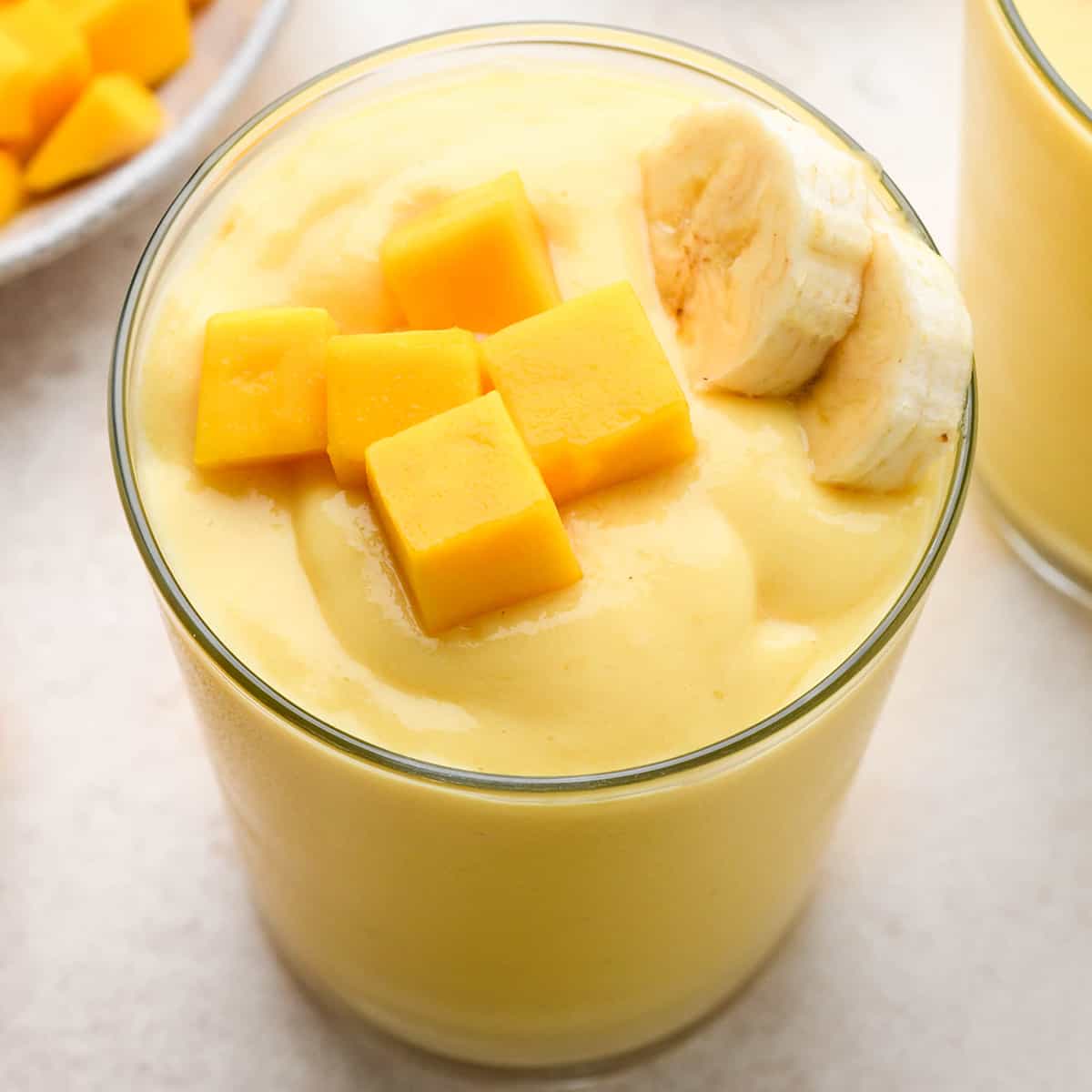 tropical smoothie in a glass topped with banana and mango