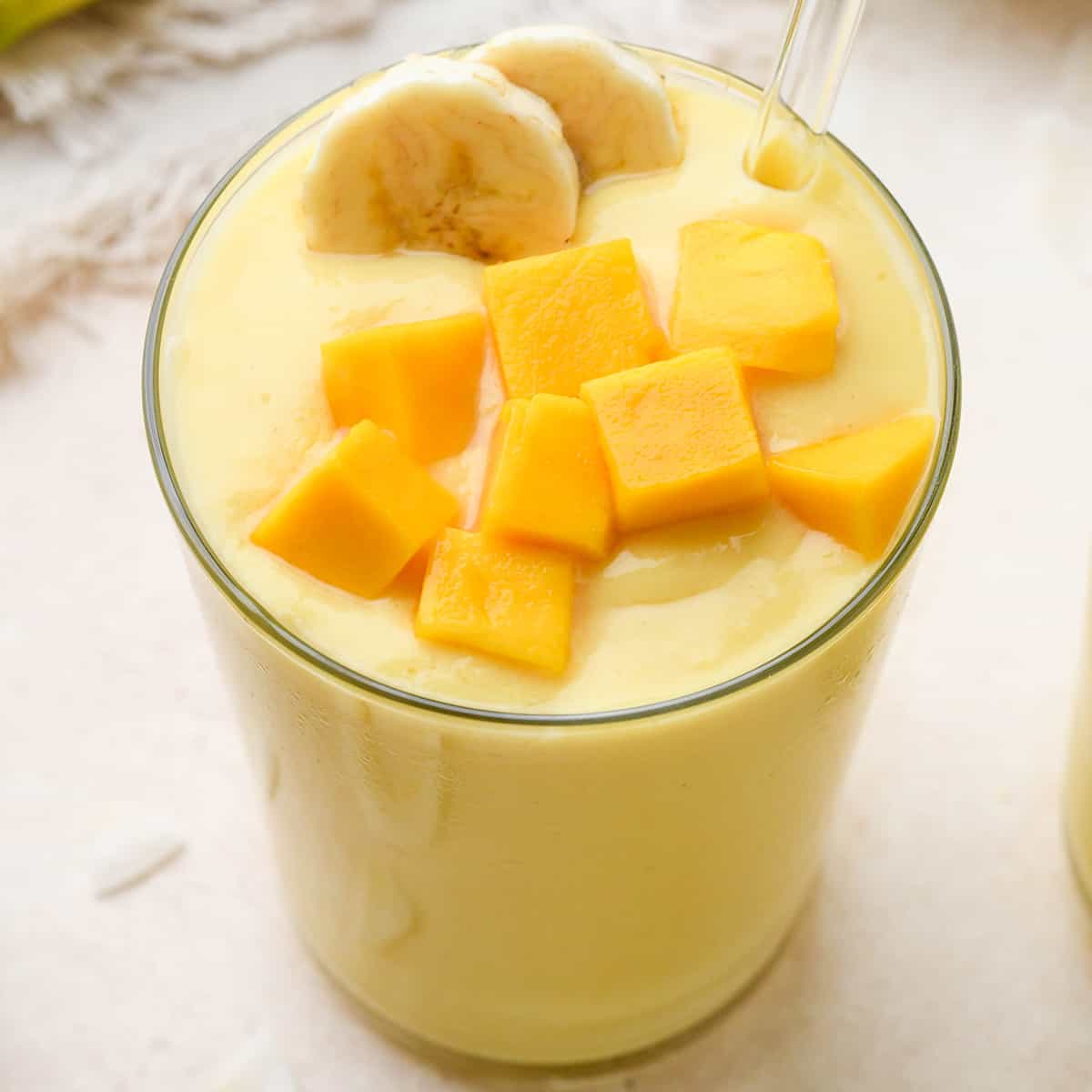 tropical smoothie in a glass topped with mango and banana