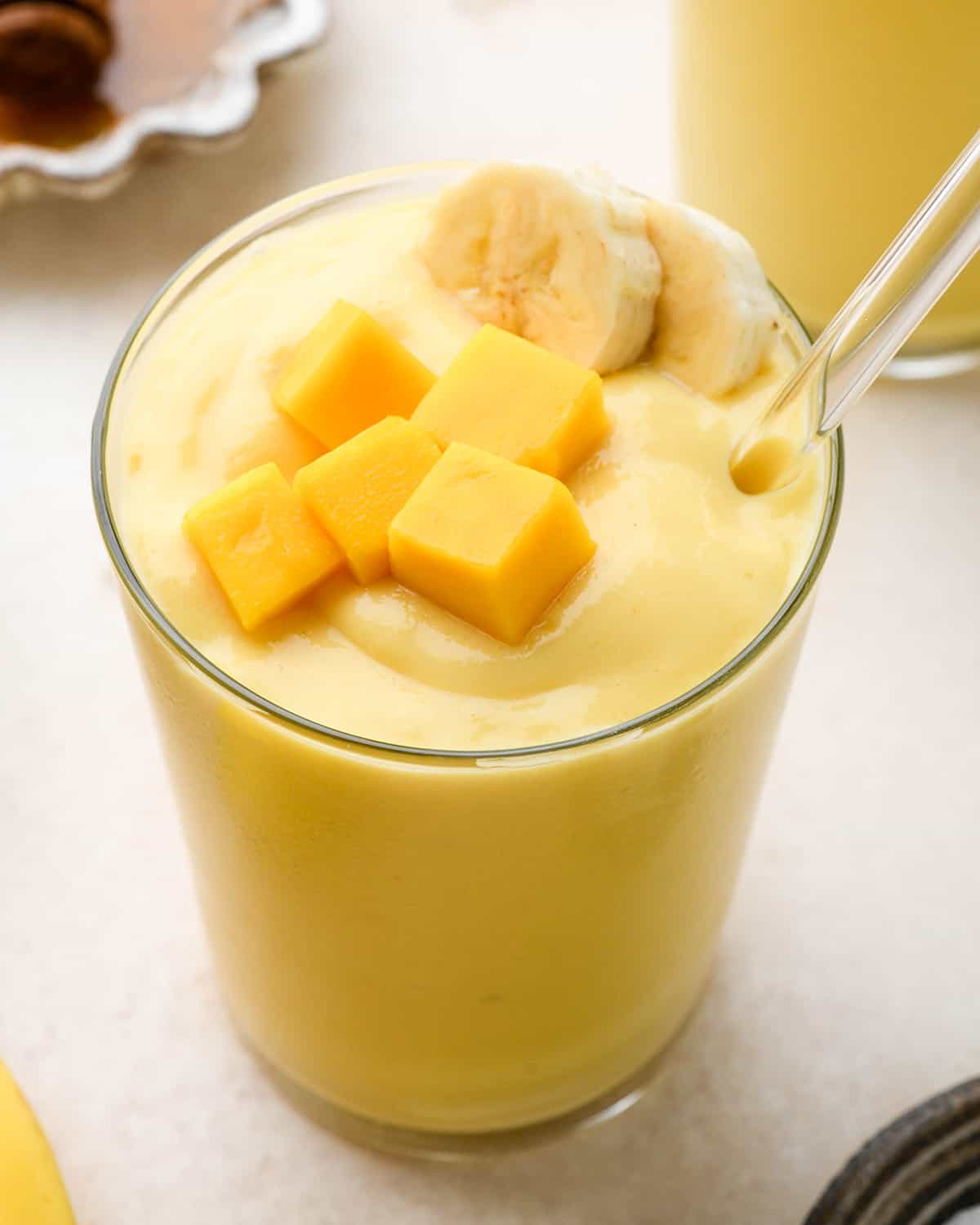 a glass of topical smoothie topped with mango and banana