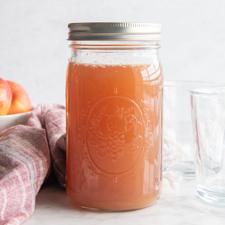 A glass jar with a lid filled with homemade apple cider