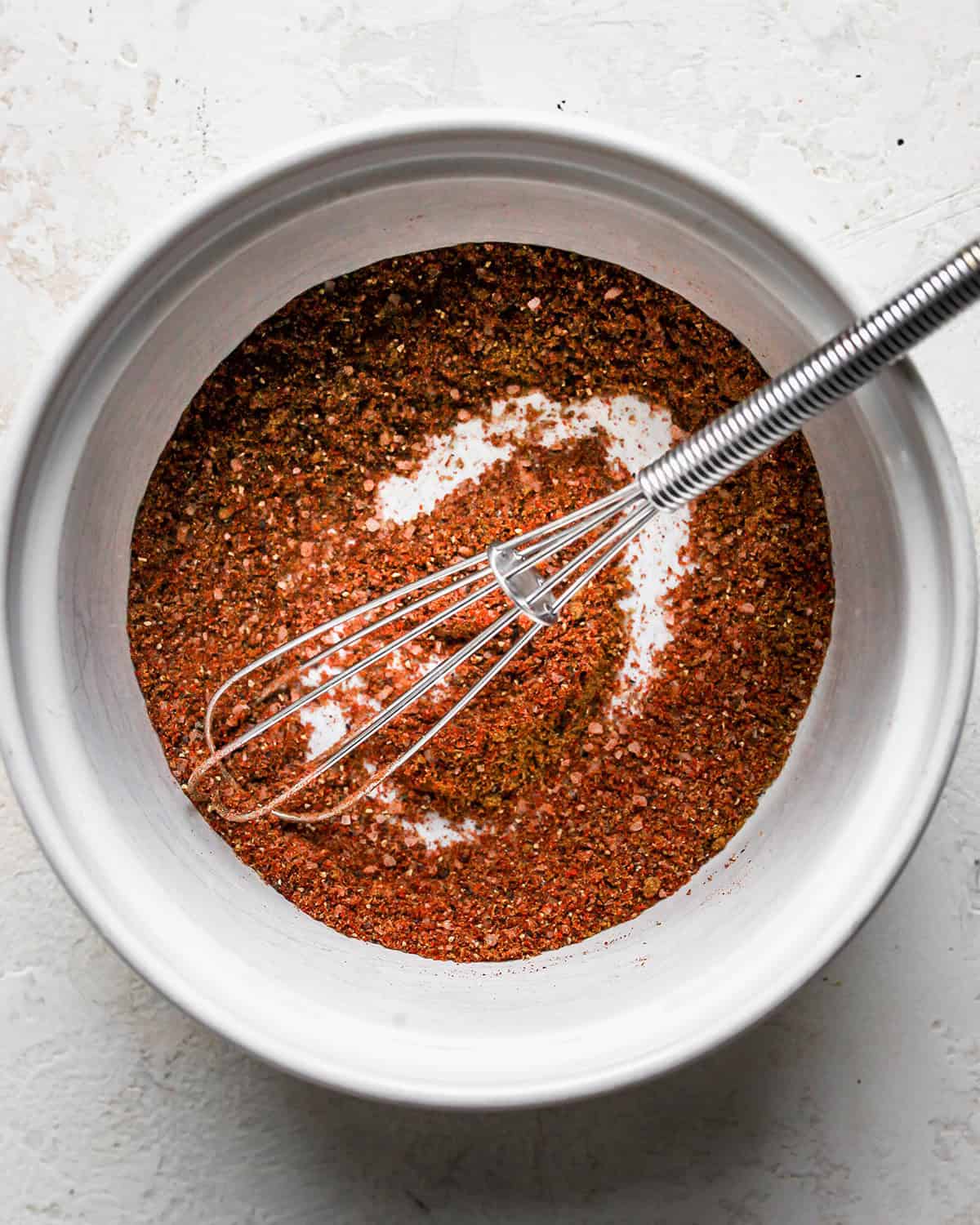 chicken fajitas seasoning mixture in a ceramic bowl with a metal whisk