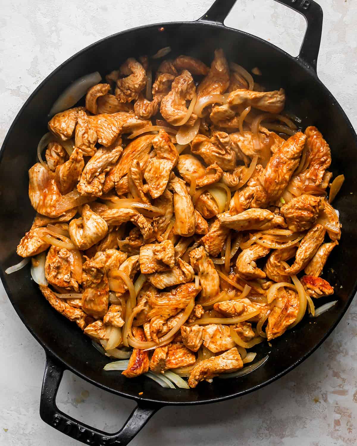 making chicken fajitas - chicken, onions and garlic in a back cast iron skillet after cooking