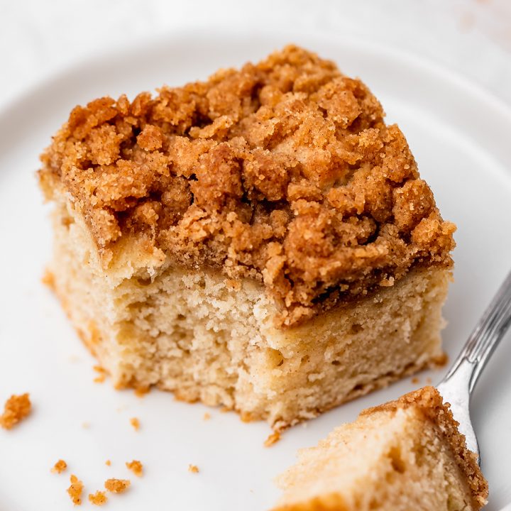 a piece of Cinnamon Coffee Cake on a plate with a bite taken out of it on a fork next to the cake