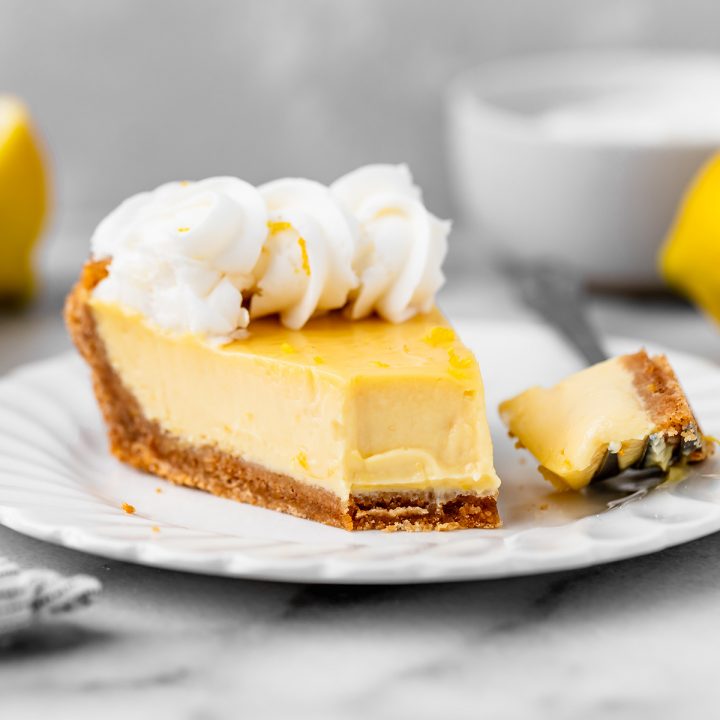 a slice of lemon pie on a plate with a bite taken out of it