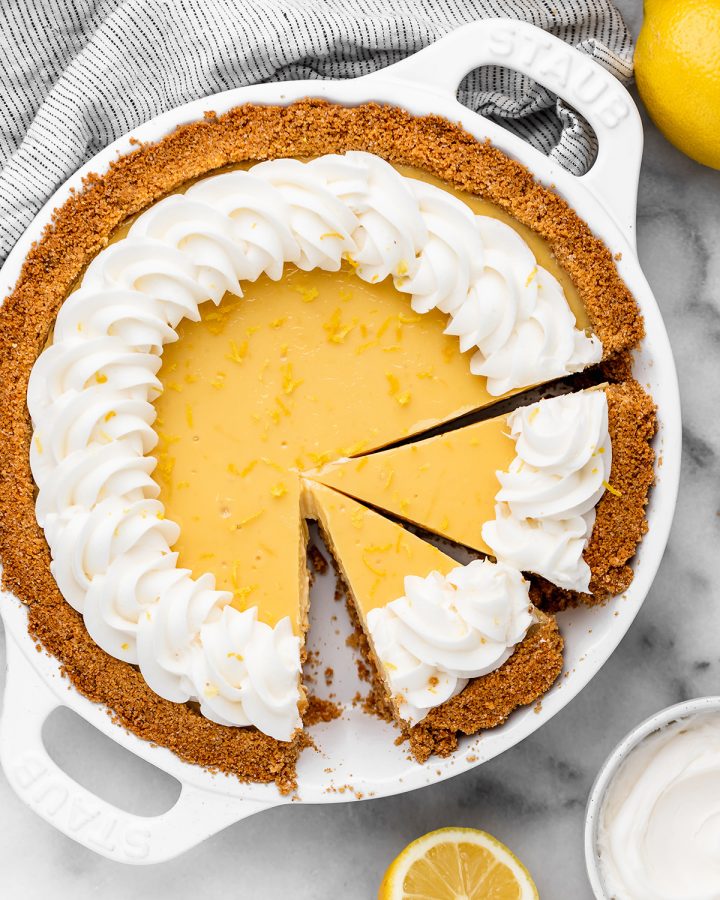 a lemon pie with whipped cream and two slices cut out of it