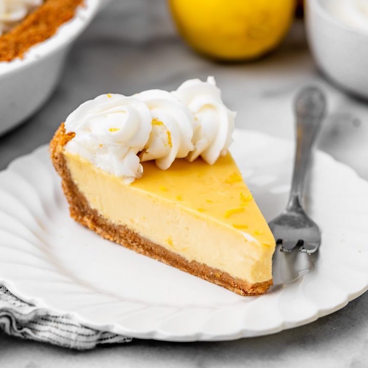 slice of Lemon Pie on a plate topped with whipped cream and lemon zest