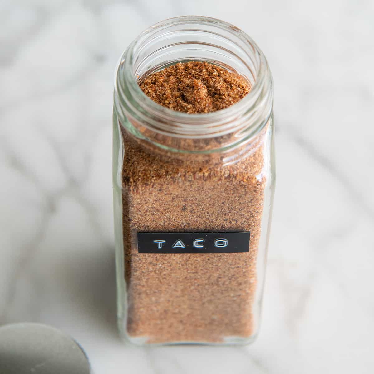 a glass jar with a black label that reads "taco" full of Homemade Taco Seasoning
