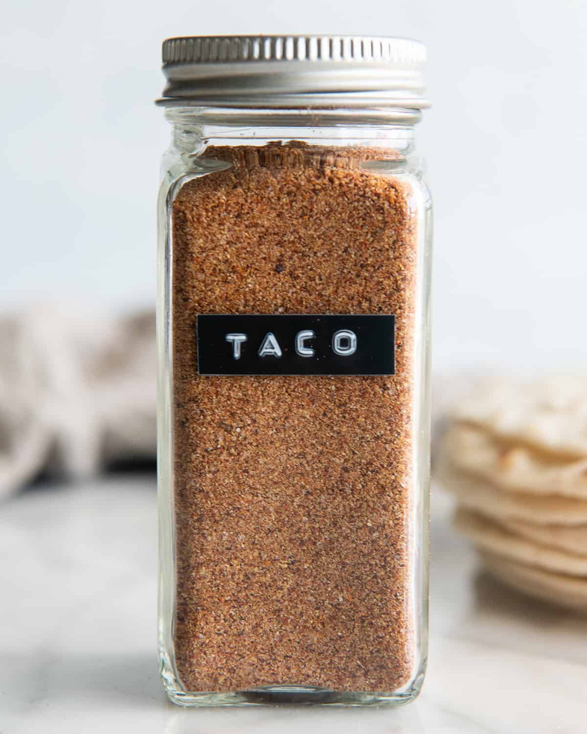 a glass spice jar of Homemade Taco Seasoning with a label "taco"