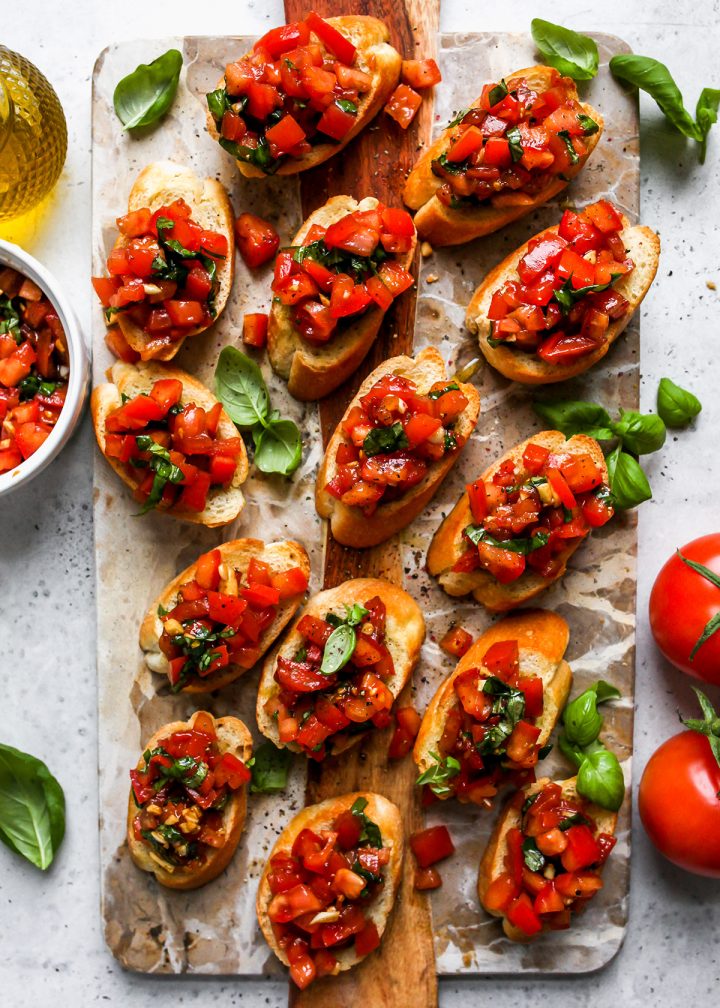 14 pieces of bread topped with tomato bruschetta on a board for serving