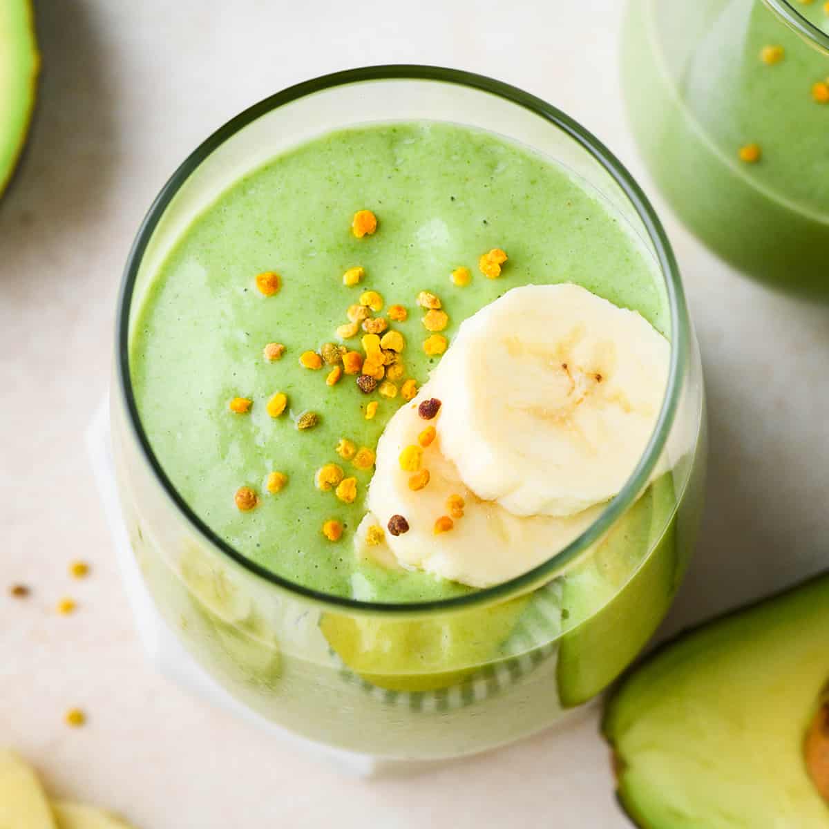 Banana Avocado Smoothie in a glass topped with sliced bananas and bee pollen