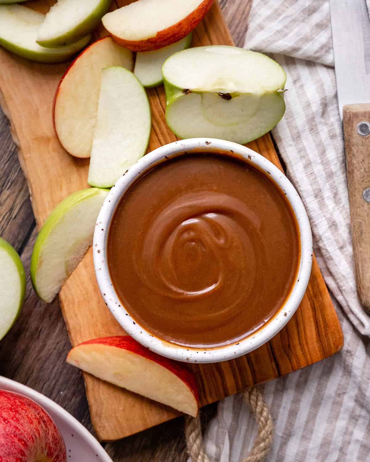 a bowl of Caramel Apple Dip surrounded by apples