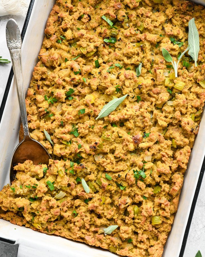 Cornbread Dressing  in a baking dish topped with fresh herbs