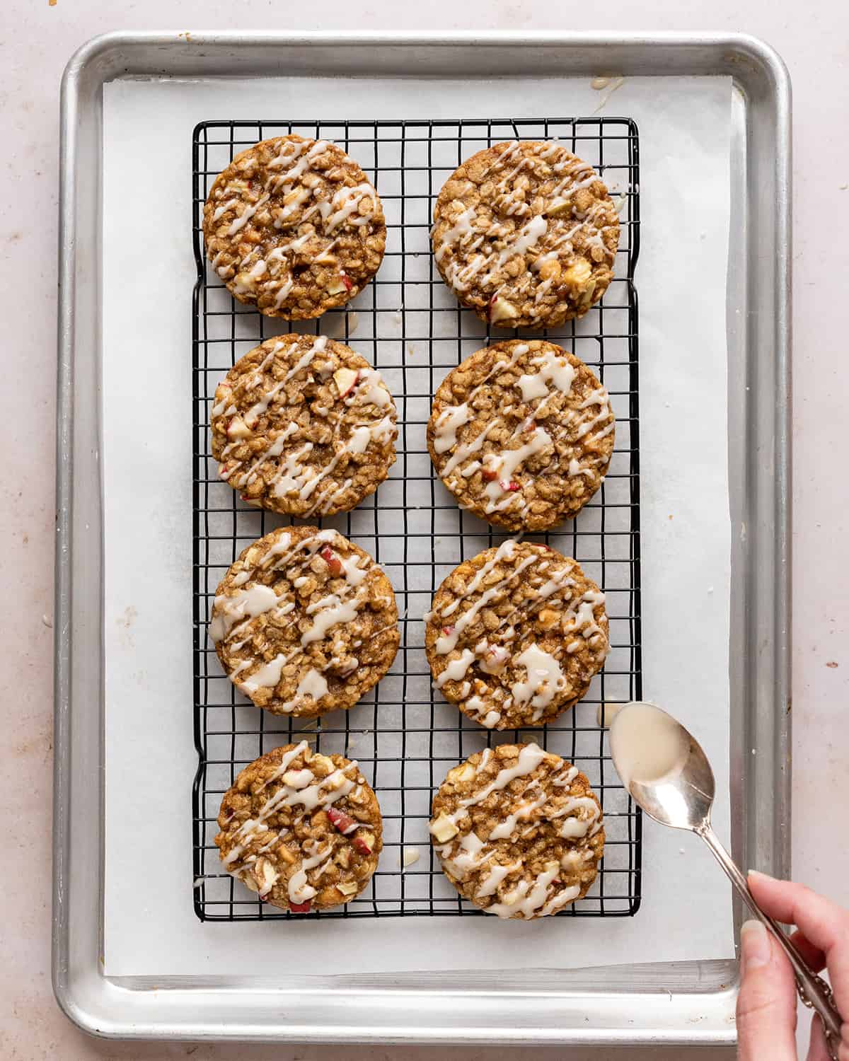 8 Oatmeal Apple Cookies on a wire rack being drizzled with glaze