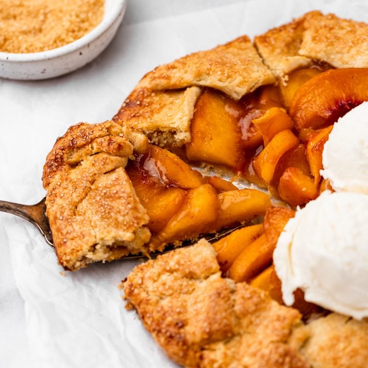 a piece being lifted out of a a Peach Galette with 3 scoops of vanilla ice cream on top