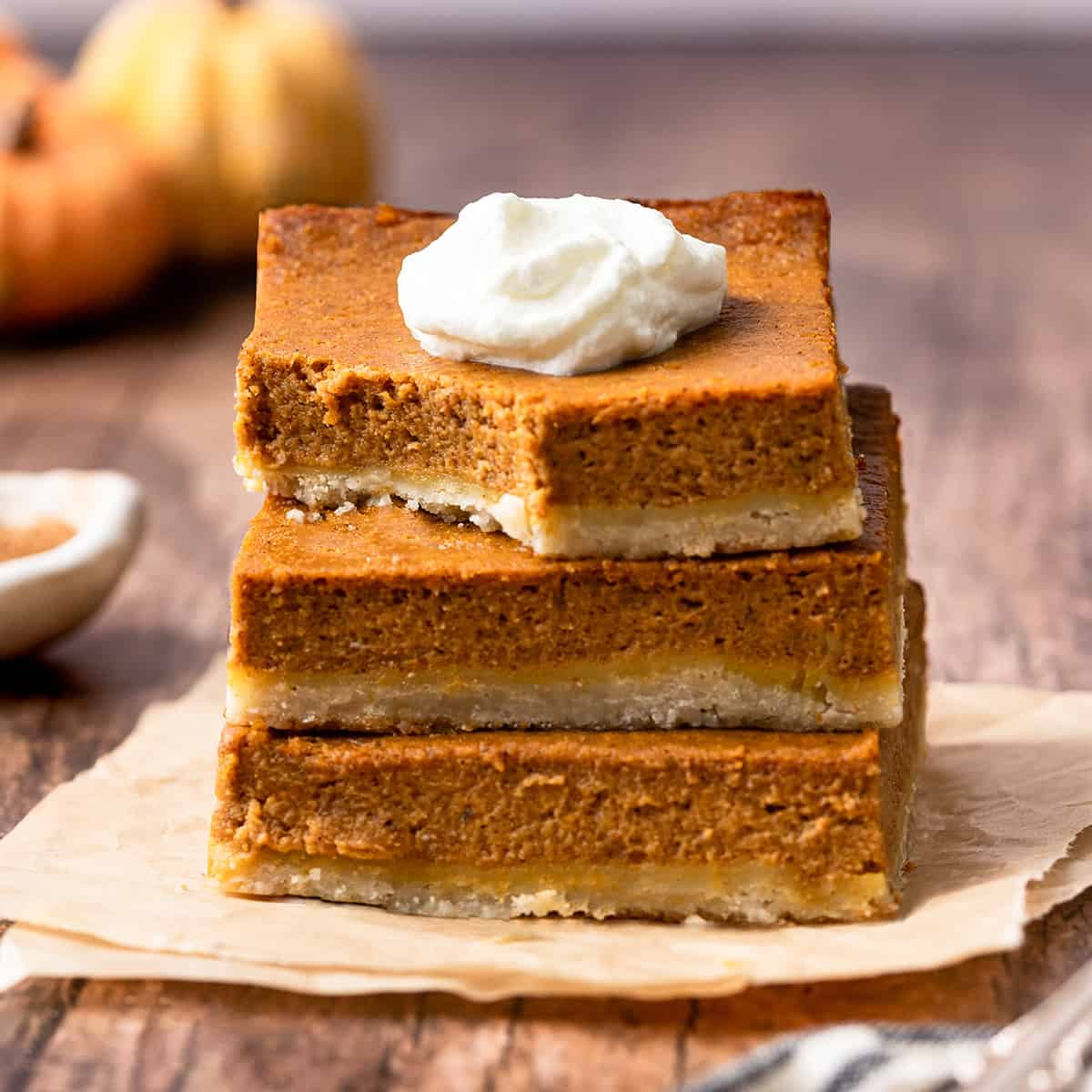 a stack of 3 Pumpkin Pie Bars with whipped cream on top 