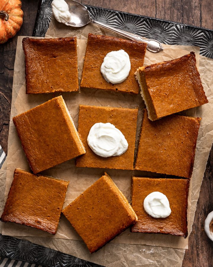 overhead photo of 9 square Pumpkin Pie Bars, 3 with whipped cream on top 