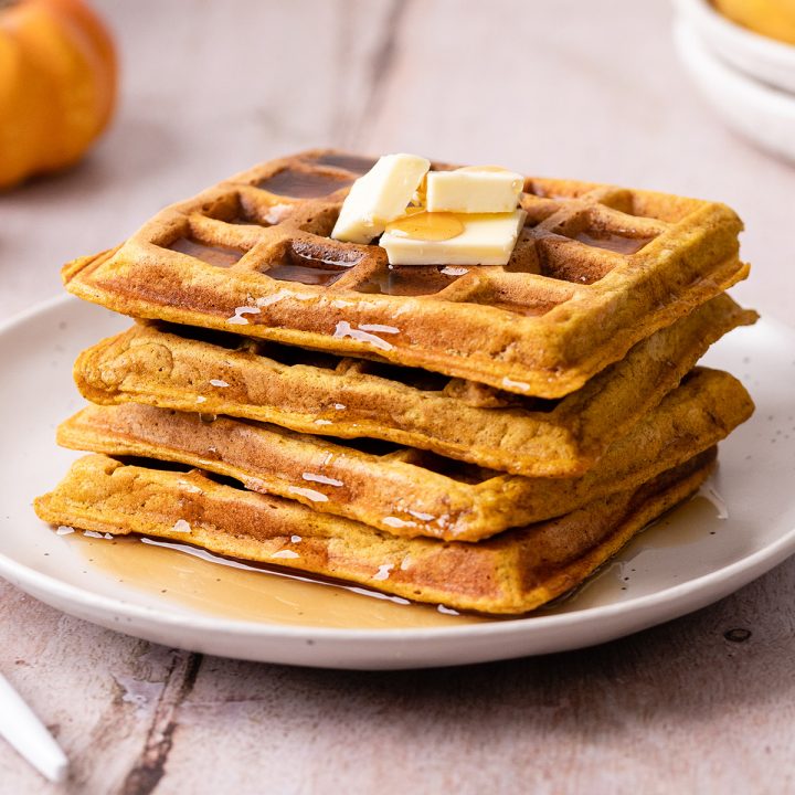 a stack of 4 Pumpkin Waffles with butter and syrup