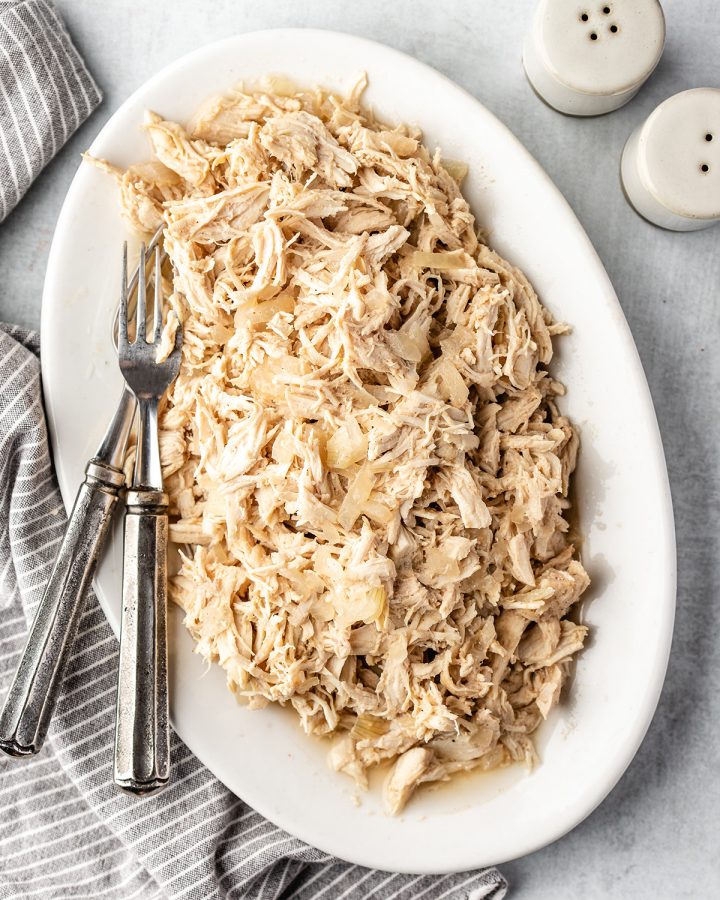 a serving dish with Slow Cooker Shredded Chicken and two forks