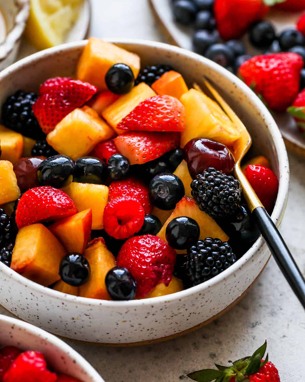 front view of summer fruit salad in a bowl with a fork
