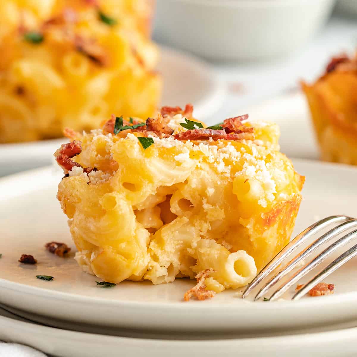 a Baked Mac & Cheese Cup on a plate with a bite taken out of it. 