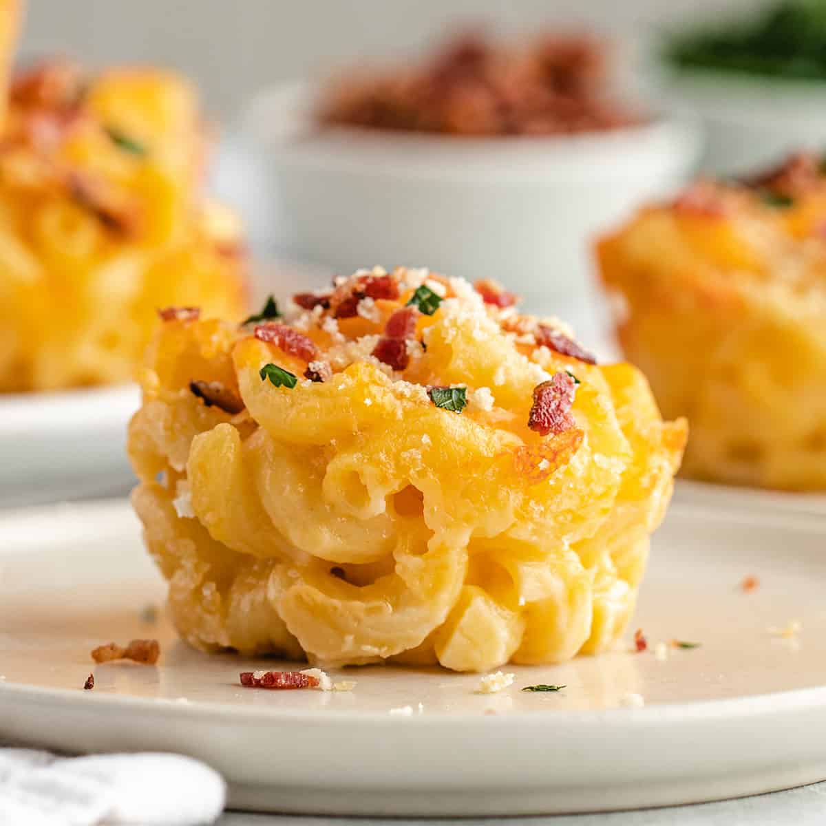 a Baked Mac & Cheese Cup topped with bacon and parsley on a plate