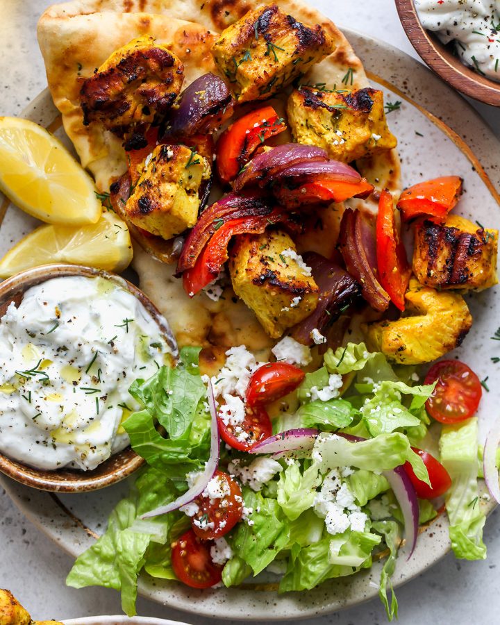 Chicken Kebabs on a plate with naan, salad and tzatziki