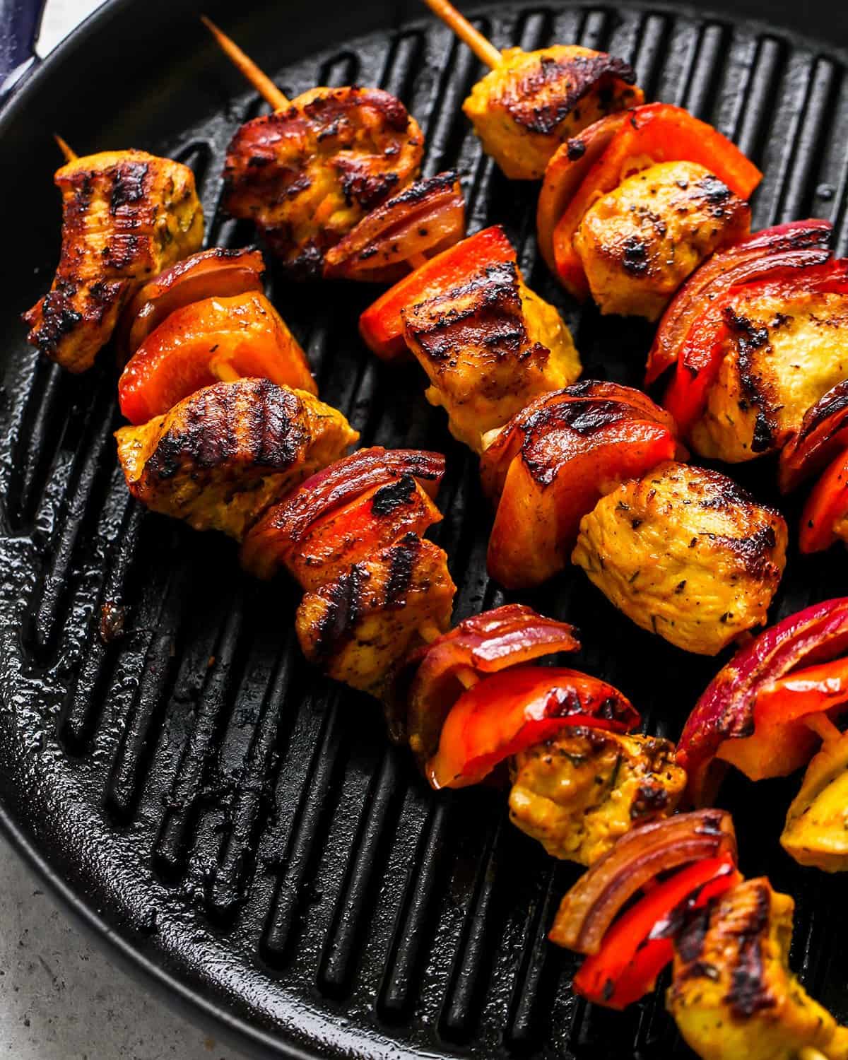 chicken kabobs being cooked on a grill pan