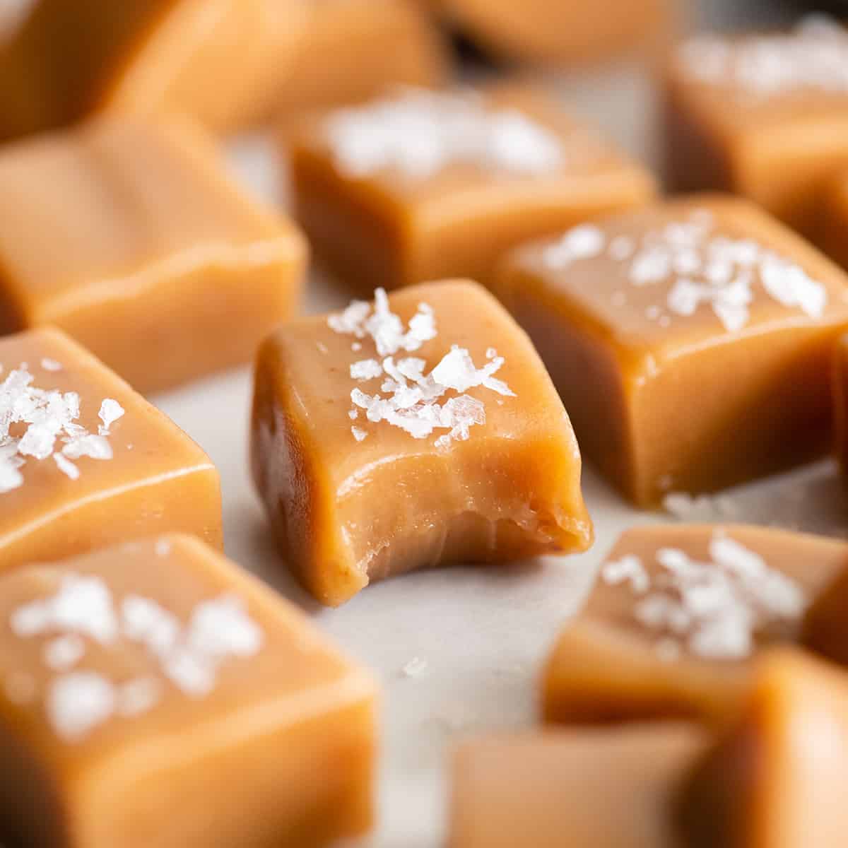 a piece of homemade caramel with a bite taken out of it topped with sea salt 