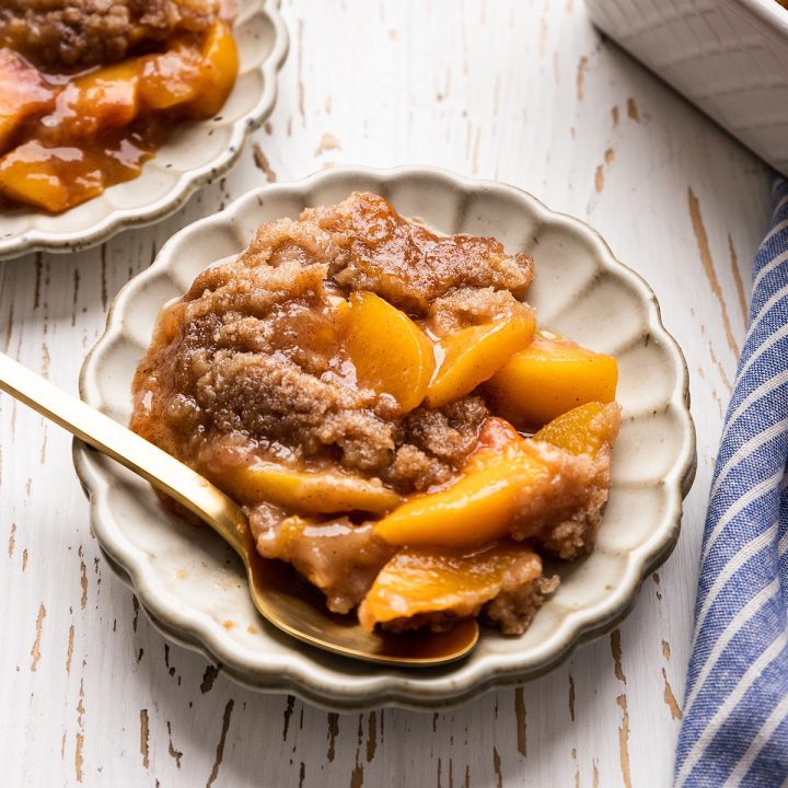 peach crumble on a plate with a spoon