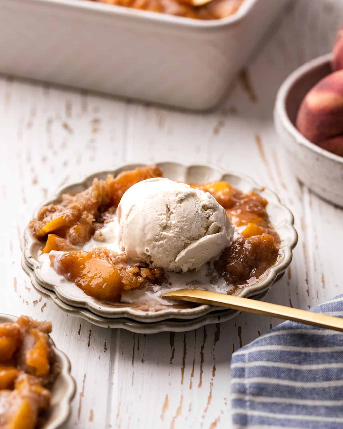 Peach Crumble on a plate with melty ice cream and a spoon