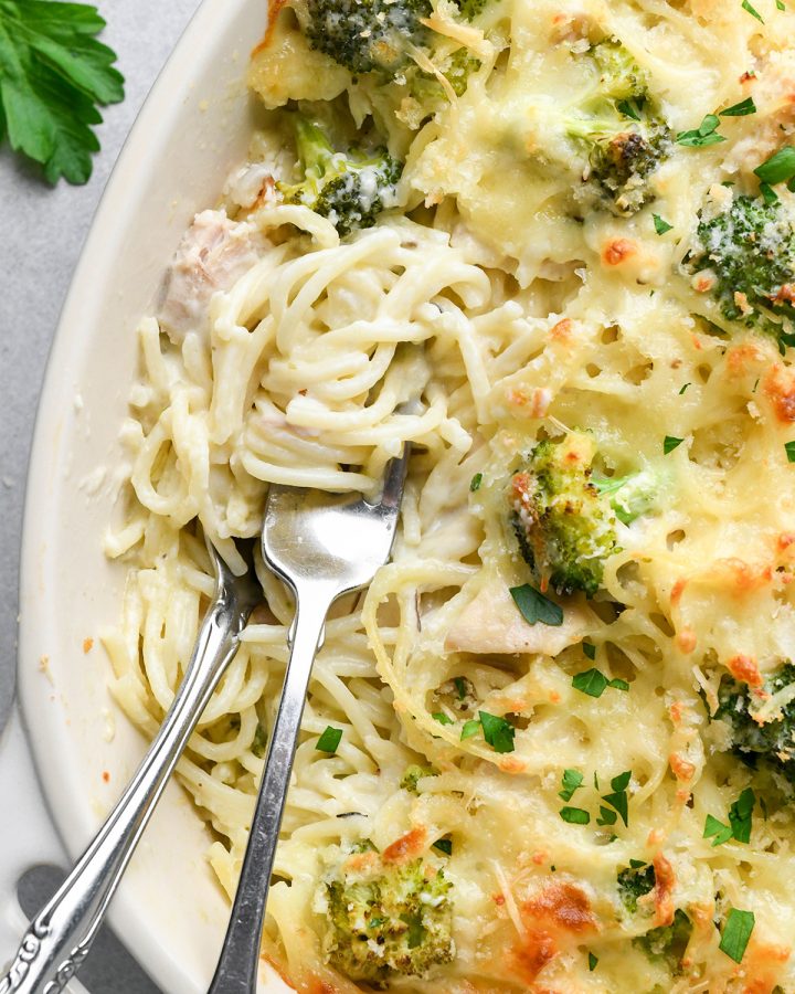 up close photo of two forks twirling pasta in a baking dish of turkey tetrazzini 