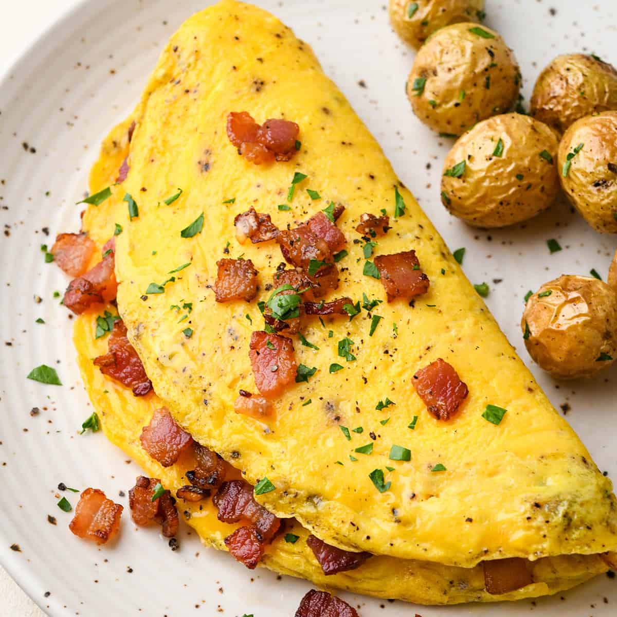an omelette on a plate with bacon and potatoes