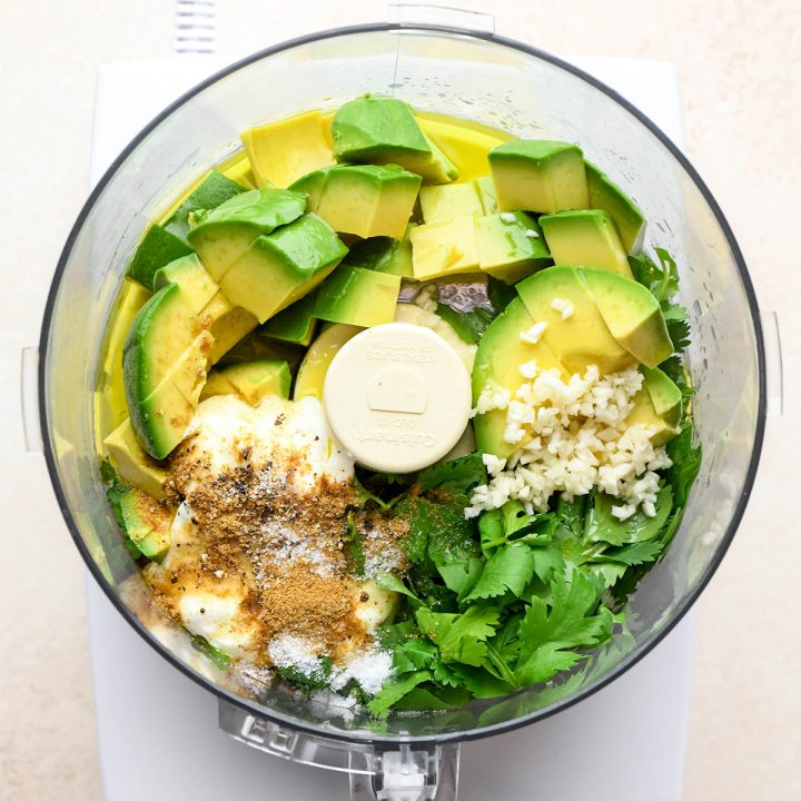 ingredients for this Cilantro Lime Avocado Dressing recipe in the container of a food processor