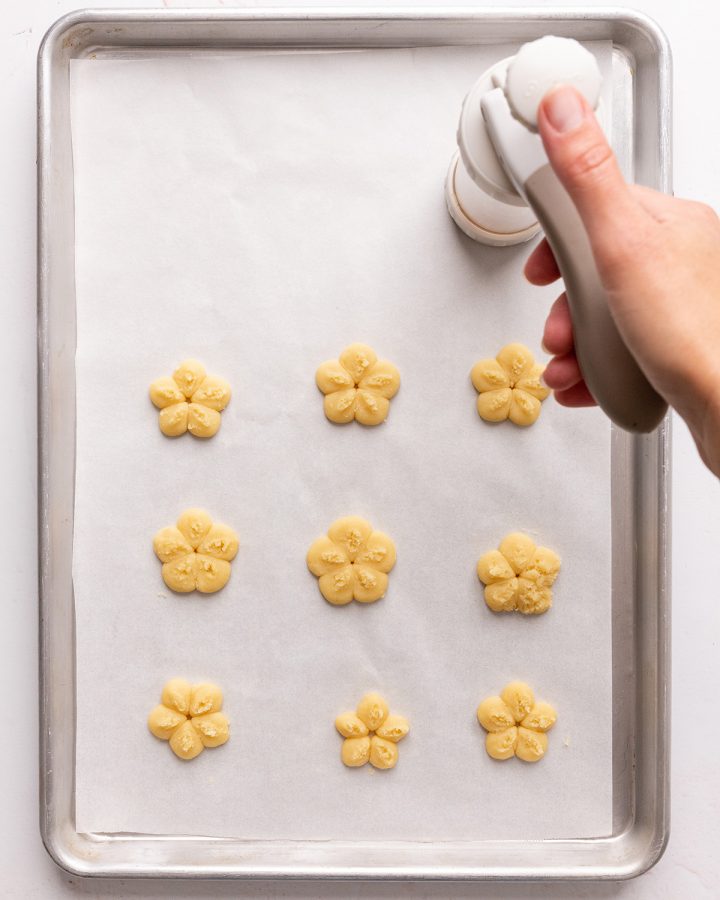 a cookie press making flower shaped butter cookies