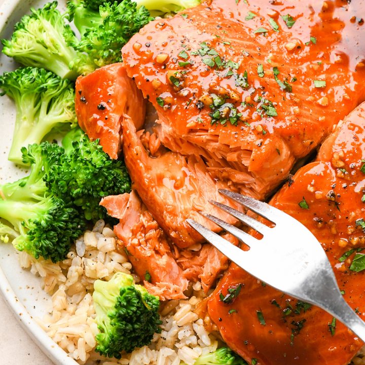 a fork taking a bite out of Maple Salmon on a plate with rice and broccoli