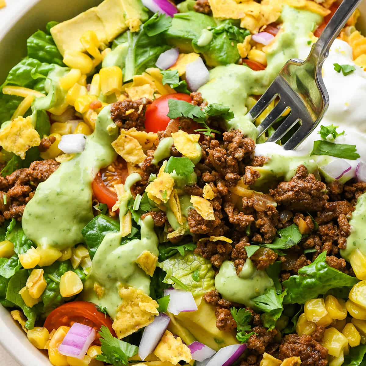 a fork taking a bite out of a bowl of taco salad