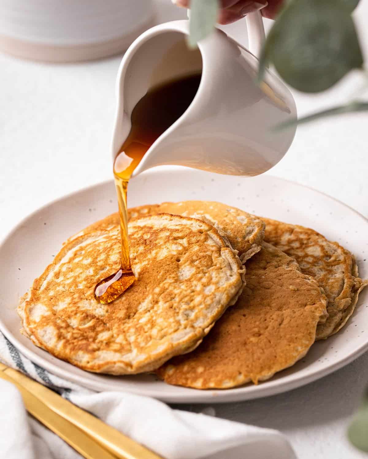 syrup being poured onto four Zucchini Pancakes on a plate