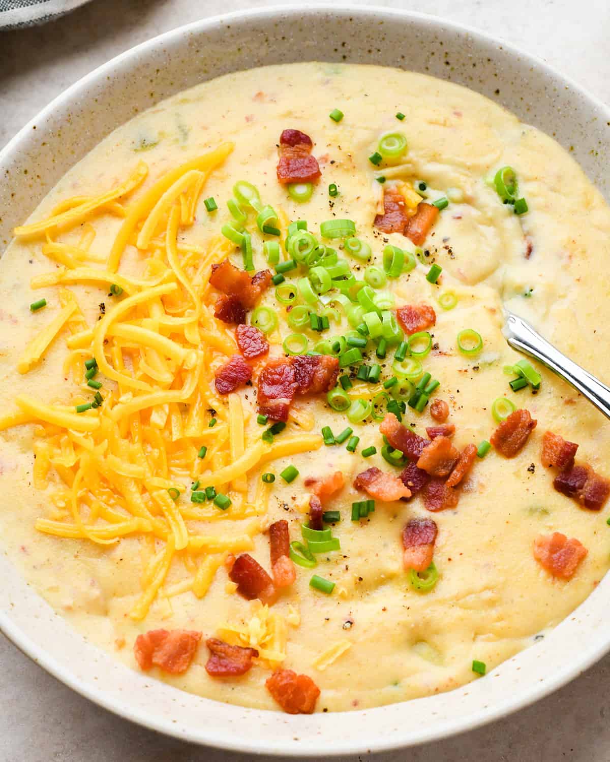 a bowl of Potato Soup topped with green onions, chives, bacon and cheese