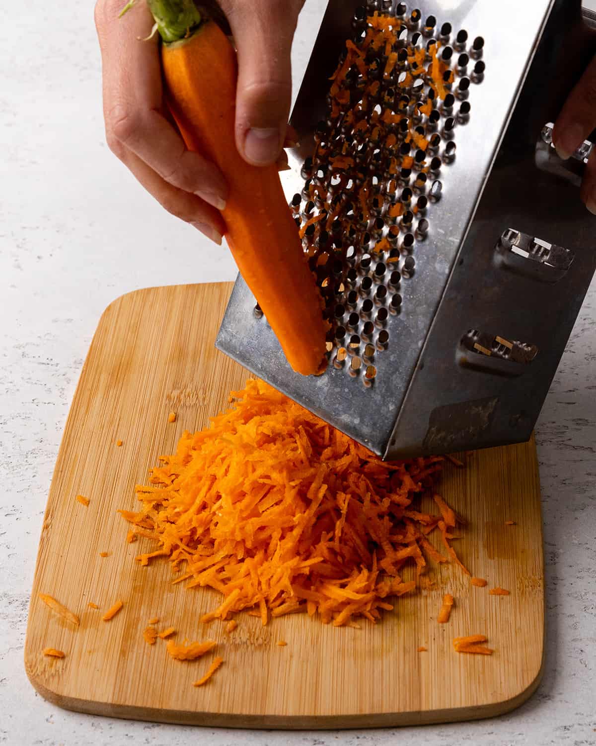 grating carrots to make this Carrot Cake Cupcakes Recipe