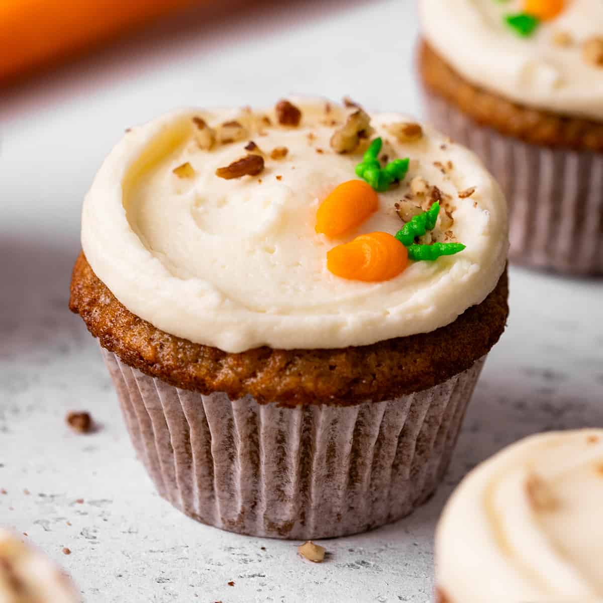 a Carrot Cake Cupcake decorated with nuts and piped frosting carrots