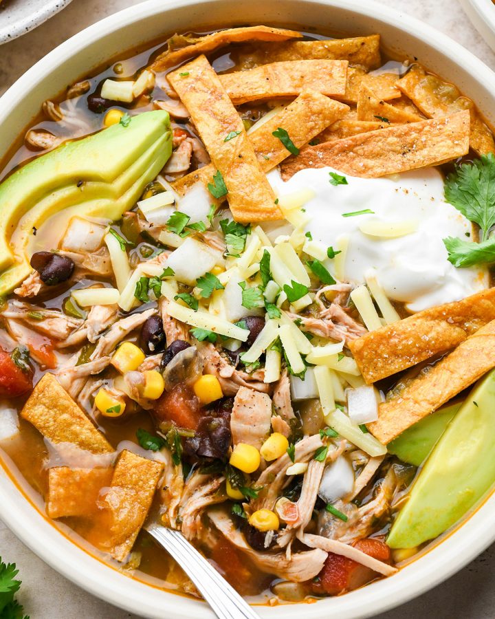 Chicken Tortilla Soup in a bowl with toppings and a spoon