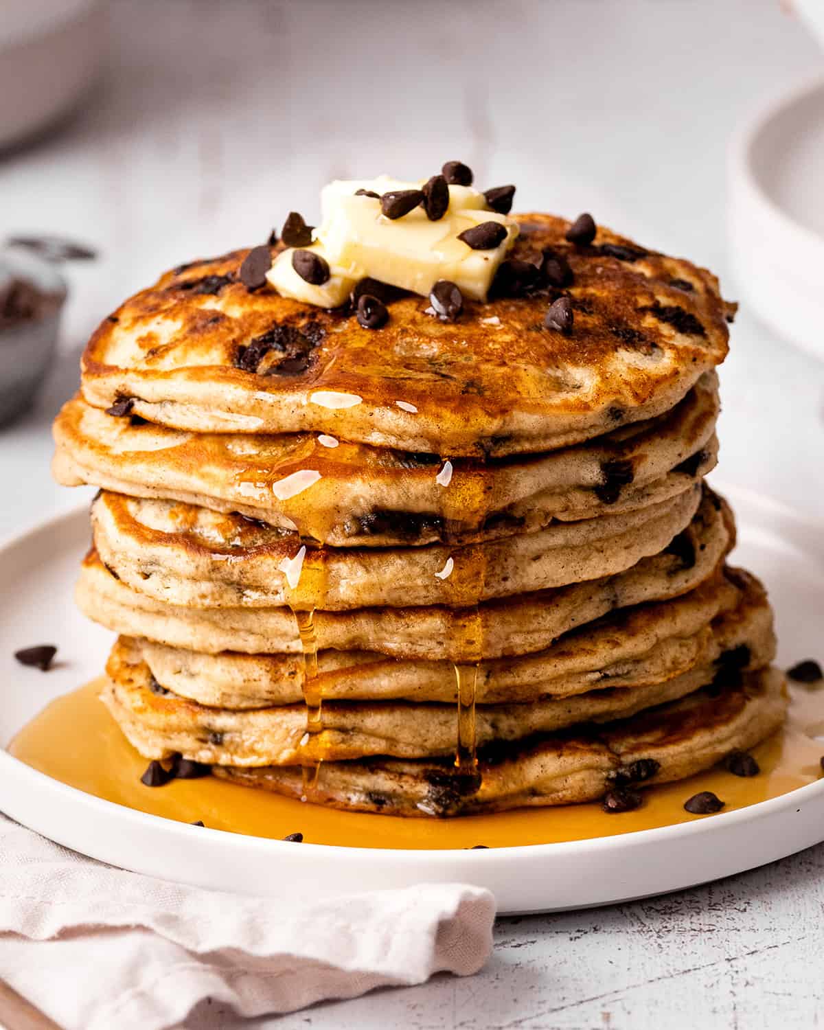 a stack of 7 Chocolate Chip Pancakes with butter and syrup and chocolate chips on top
