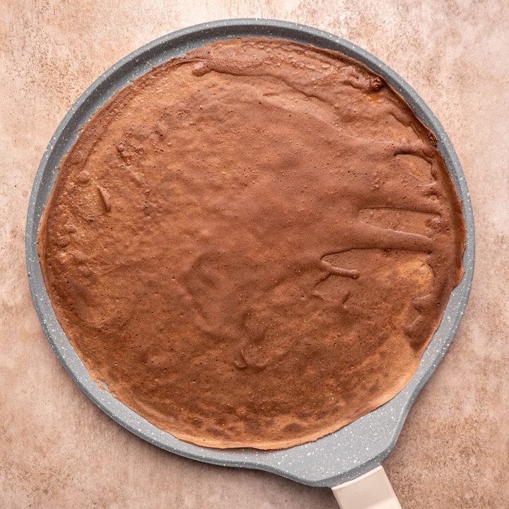 Chocolate crepes being cooked in a crepe pan