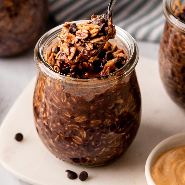 a spoon taking a scoop of Chocolate Peanut Butter Overnight Oats out of a jar