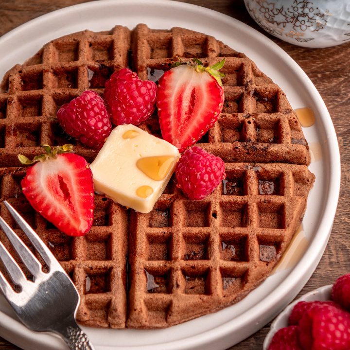 1 Chocolate Waffle on a plate with butter, syrup and berries