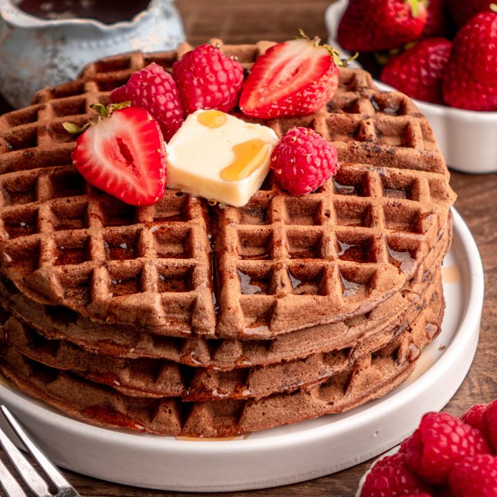 a stack of 3 Chocolate Waffles with butter, syrup and fresh berries
