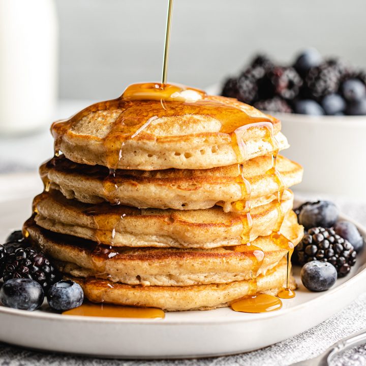 a stack of 5 Fluffy Homemade Pancakes with syrup being poured over the top of them